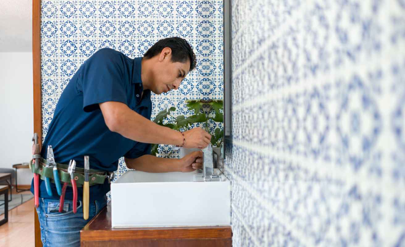 Plumber fixing a leak in a faucet in a bathroom's sink