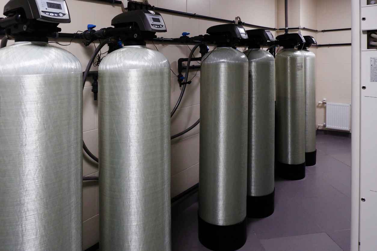 several water softener filters for water stand in a row. water treatment system