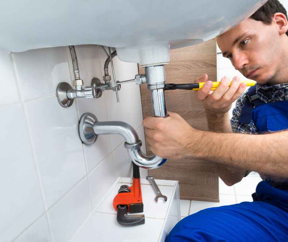 A plumber working on a leaking sink